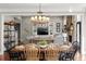 Formal dining room area with elegant light fixture open to living room with stone fireplace at 6880 Nantucket Cv, Cumming, GA 30041