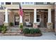 Charming front porch with stone columns, rocking chairs, and an American flag accenting the brick facade at 6880 Nantucket Cv, Cumming, GA 30041