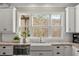 Bright kitchen with a farmhouse sink and a large window that offers a scenic outdoor view at 6880 Nantucket Cv, Cumming, GA 30041