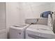 Bright laundry room features modern, white washer and dryer, complemented by an iron and wire shelving unit at 2690 Valvedere Dr, Brookhaven, GA 30319