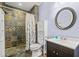 Bathroom featuring walk-in shower with decorative tile surround and neutral colored vanity and toilet at 6350 Bridge Brook Ovlk, Cumming, GA 30028