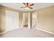 Neutral bedroom with ceiling fan, carpet, and ensuite access to a bathroom, featuring double door closet at 6350 Bridge Brook Ovlk, Cumming, GA 30028