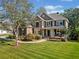 Two story home showcasing a well-manicured lawn, stone accents, and a charming covered porch area at 6350 Bridge Brook Ovlk, Cumming, GA 30028