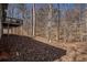 Backyard of house covered in fallen brown leaves and forest scenery at 6575 Roundhill Ct, Cumming, GA 30040