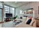 Modern living room featuring a concrete accent wall, hardwood floors, and large windows with cityscape views at 923 Peachtree Ne St # 1527, Atlanta, GA 30309