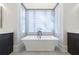 A freestanding white bathtub is centered between two dark wooden vanities with elegant fixtures at 200 Rivermere Way, Sandy Springs, GA 30350