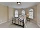 Cozy bedroom featuring a wrought iron bed frame, carpeted floors, and three arched windows at 525 Water Shadow Ln, Alpharetta, GA 30022