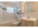 Bathroom featuring a white tiled tub, toilet, vanity, and a decorative mirror at 885 Briarcliff Ne Rd # D3, Atlanta, GA 30306