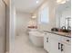 Bright bathroom featuring a freestanding tub, double vanity, and marble-look tile flooring at 2286 Cadenza Cir, Dacula, GA 30019