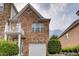 Brick townhouse featuring a white garage door, round window, and small balcony at 10828 Yorkwood Street, Johns Creek, GA 30097