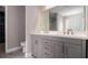Bathroom vanity with double sinks, large mirror, modern hardware, and gray cabinetry at 11643 Sarah Loop, Hampton, GA 30228