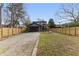Large backyard with gravel driveway, wooden fence, and various mature trees, offering ample space and privacy at 1742 Ridgeway Nw Ave, Atlanta, GA 30318