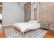 Bright bedroom featuring a bed, exposed brick wall, and modern rug at 87 Peachtree Sw St # 204, Atlanta, GA 30303