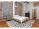 Main bedroom with brick accent wall, wood floors, exposed ductwork, and neutral decor at 87 Peachtree Sw St # 204, Atlanta, GA 30303
