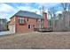 Brick home featuring a rear deck, balcony, and attached garage, set against a backdrop of mature trees and open space at 2650 Riverfront Dr, Snellville, GA 30039