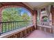 Private covered balcony features brick arches, iron railing, and a view of the surrounding trees and blue skies at 795 Ponce De Leon Ne Pl # C3, Atlanta, GA 30306