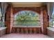 Private covered balcony features brick arches, iron railing, and a view of the surrounding trees and blue skies at 795 Ponce De Leon Ne Pl # C3, Atlanta, GA 30306