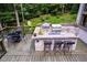 Outdoor deck with built-in grill, stone bar with seating, and dining area, surrounded by trees at 385 Grimes Bridge Rd, Roswell, GA 30075
