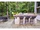 Outdoor deck with built-in stone kitchen, bar seating, and dining table surrounded by lush greenery at 385 Grimes Bridge Rd, Roswell, GA 30075