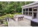 Outdoor deck with built-in stone kitchen, bar seating, and hot tub surrounded by lush greenery at 385 Grimes Bridge Rd, Roswell, GA 30075