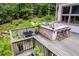 Outdoor deck featuring a built-in stone kitchen, bar seating, and a dining table surrounded by lush greenery at 385 Grimes Bridge Rd, Roswell, GA 30075