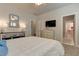 Bedroom with a large bed, dresser with a TV, a grey-framed mirror, and entryways to the bathroom and hallway at 114 Rock Creek Ln, Canton, GA 30114