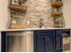 Finished basement kitchenette with blue cabinets, brick backsplash, stainless steel sink and dishwasher at 114 Rock Creek Ln, Canton, GA 30114