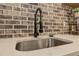 Close up of the finished basement kitchenette sink with brick backsplash and stainless faucet at 114 Rock Creek Ln, Canton, GA 30114