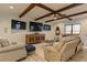 Living room showcasing wood beam ceilings, a large sectional, multiple TVs, and hardwood floors at 114 Rock Creek Ln, Canton, GA 30114