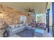 Cozy covered patio featuring stone accent wall, ceiling fan, and comfortable outdoor seating area at 114 Rock Creek Ln, Canton, GA 30114