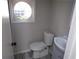 Cozy bathroom with a modern toilet, vanity and sink, complemented by a unique round window at 2401 Northlake Ct, Atlanta, GA 30345