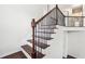 Staircase with dark wood treads, white risers and decorative wrought iron railing at 5932 Vinings Vintage Way, Mableton, GA 30126