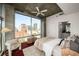 Bedroom with city views from large windows, ceiling fan, neutral decor, and ensuite bath at 943 Peachtree Ne St # 1108, Atlanta, GA 30309