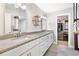 Stylish bathroom featuring double sinks with granite countertops, decorative shelving, and a walk-in closet at 3465 Callie Still Rd, Lawrenceville, GA 30045