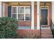 Inviting brick front porch with white columns, black shutters and a freshly painted black front door at 4790 Maristone Landing Way, Cumming, GA 30040
