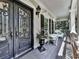 Covered front porch with decorative front door, white wicker furniture, and stone accents at 1012 Jubilee Way, Powder Springs, GA 30127