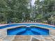 Backyard pool area with in-ground hot tub and stone surround, partially enclosed by dark metal fence at 1012 Jubilee Way, Powder Springs, GA 30127