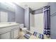 This blue-walled bathroom features a single sink vanity, a toilet, and a bathtub with a striped shower curtain at 3999 Craggy Perch, Douglasville, GA 30135