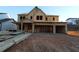 Image shows a house in the framing stage of construction with a three-car garage and visible lumber at 436 Maypop Lane, Woodstock, GA 30188