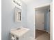 Well-lit bathroom featuring a sink with a mirror, soft blue walls, and a doorway to another room at 69 New Brunswick Ct, Suwanee, GA 30024