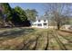 View of the white, two-story home from the yard with an exterior door and landscaping at 8404 Majors Rd, Cumming, GA 30041