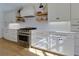 Modern kitchen featuring white cabinetry, stainless steel appliances, floating shelves, and a gas range stove at 8404 Majors Rd, Cumming, GA 30041