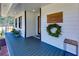 Inviting covered porch with a 'Welcome' sign, wreath, and stylish blue flooring perfect for relaxing outdoors at 8404 Majors Rd, Cumming, GA 30041