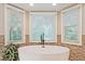 Close-up of bright bathroom soaking tub featuring three windows and mosaic tile at 1590 Greyson Rdg, Marietta, GA 30062