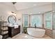 Bright bathroom featuring a soaking tub in front of a bay window, glass shower, and dark wood vanity at 1590 Greyson Rdg, Marietta, GA 30062