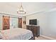 Spacious bedroom featuring a chandelier, barn doors to the bathroom, and a dark wood dresser with a large TV at 1590 Greyson Rdg, Marietta, GA 30062