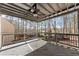 Large, covered back deck featuring a ceiling fan and a serene view of the treed backyard at 3595 Ansley Park Dr, Suwanee, GA 30024