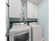 Functional laundry room featuring a modern washer and dryer set under white cabinets at 3595 Ansley Park Dr, Suwanee, GA 30024