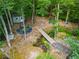 Private backyard retreat with a playset, shed, fire pit, hammock, creek, and bridge surrounded by a lush, wooded setting at 2480 Flint Creek Dr, Cumming, GA 30041