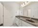 Bright bathroom boasts double sink vanity with dark countertops and framed mirror, next to a white painted door at 2480 Flint Creek Dr, Cumming, GA 30041